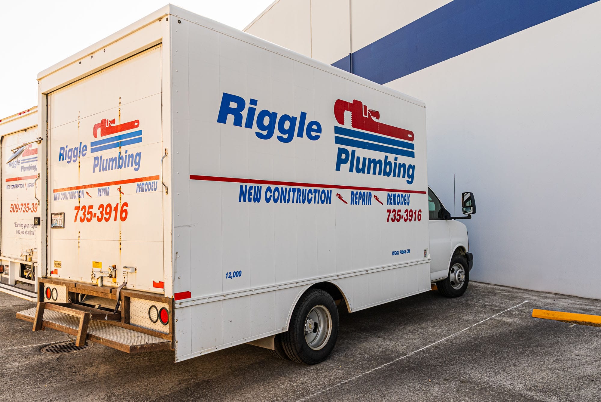 Plumbing company truck parked by building.