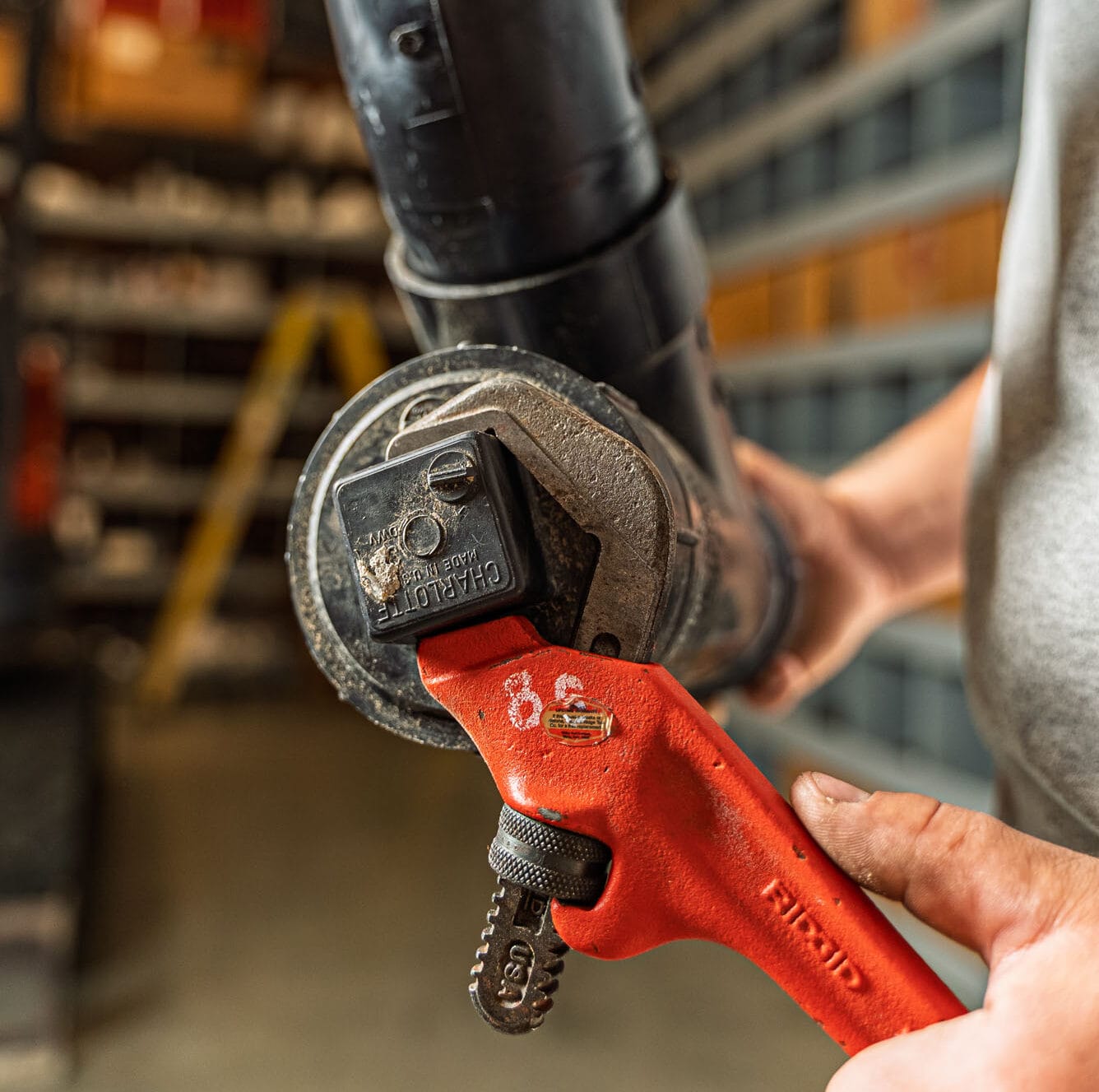 Riggle_Plumbing_0070 Person using a red pipe wrench on plumbing