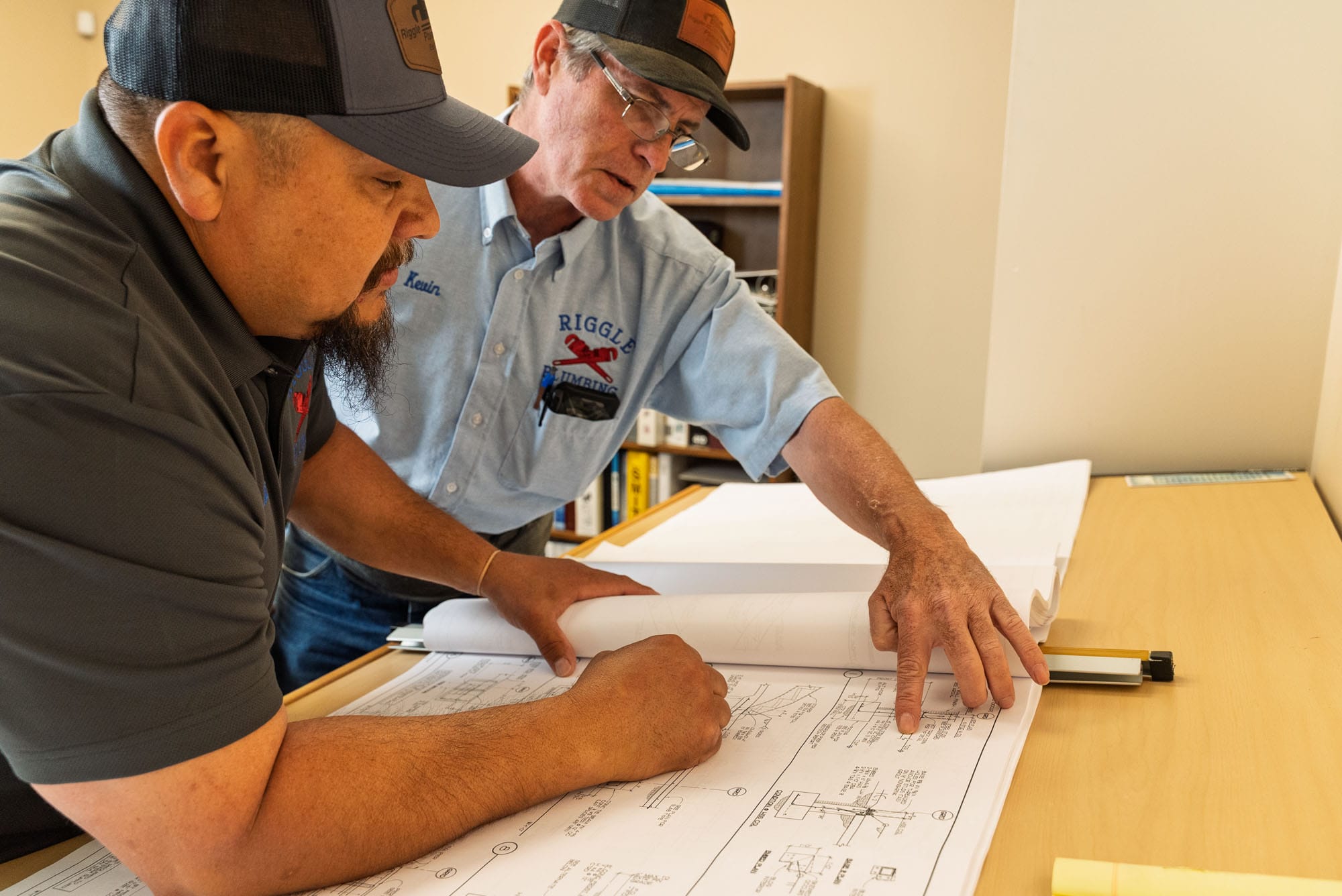 Two men discussing architectural plans on a table.