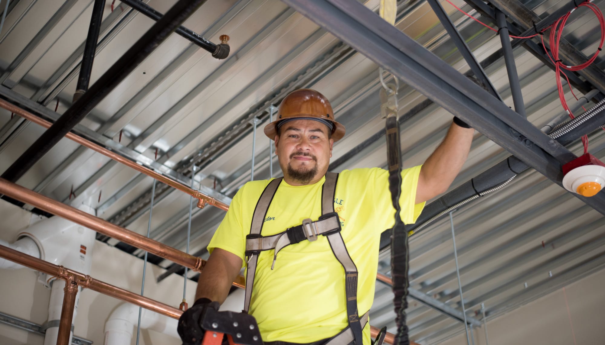 Victor Vega Construction worker on ladder with hard hat, smiling.