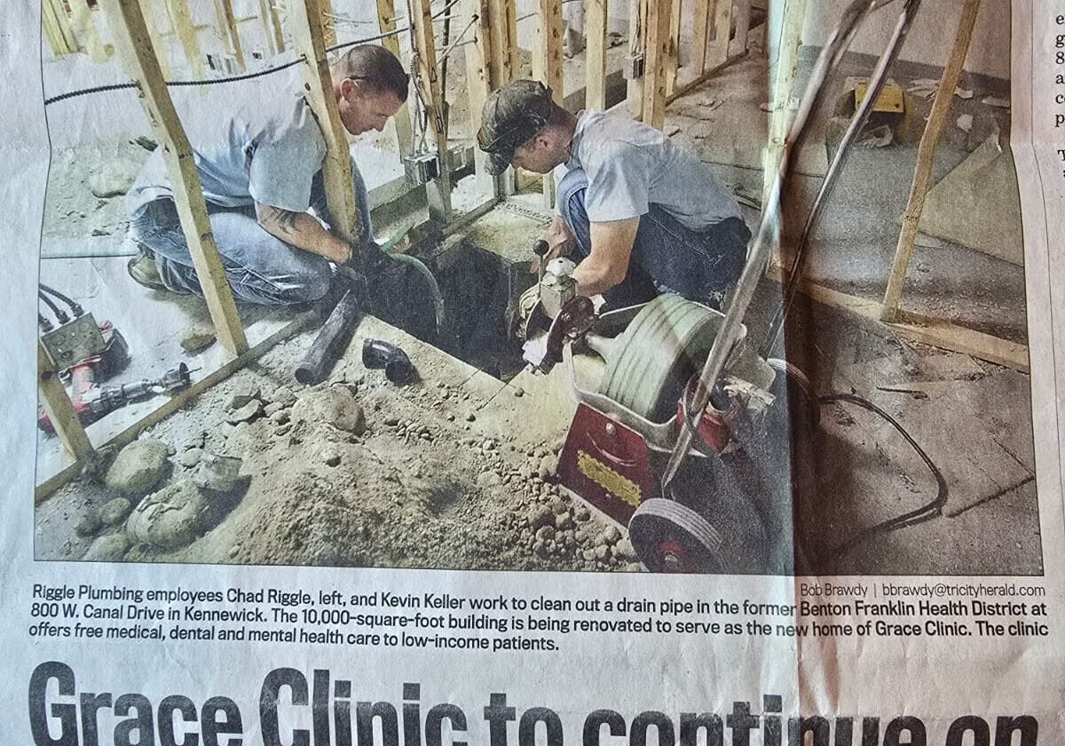 Workers cleaning drain at construction site.