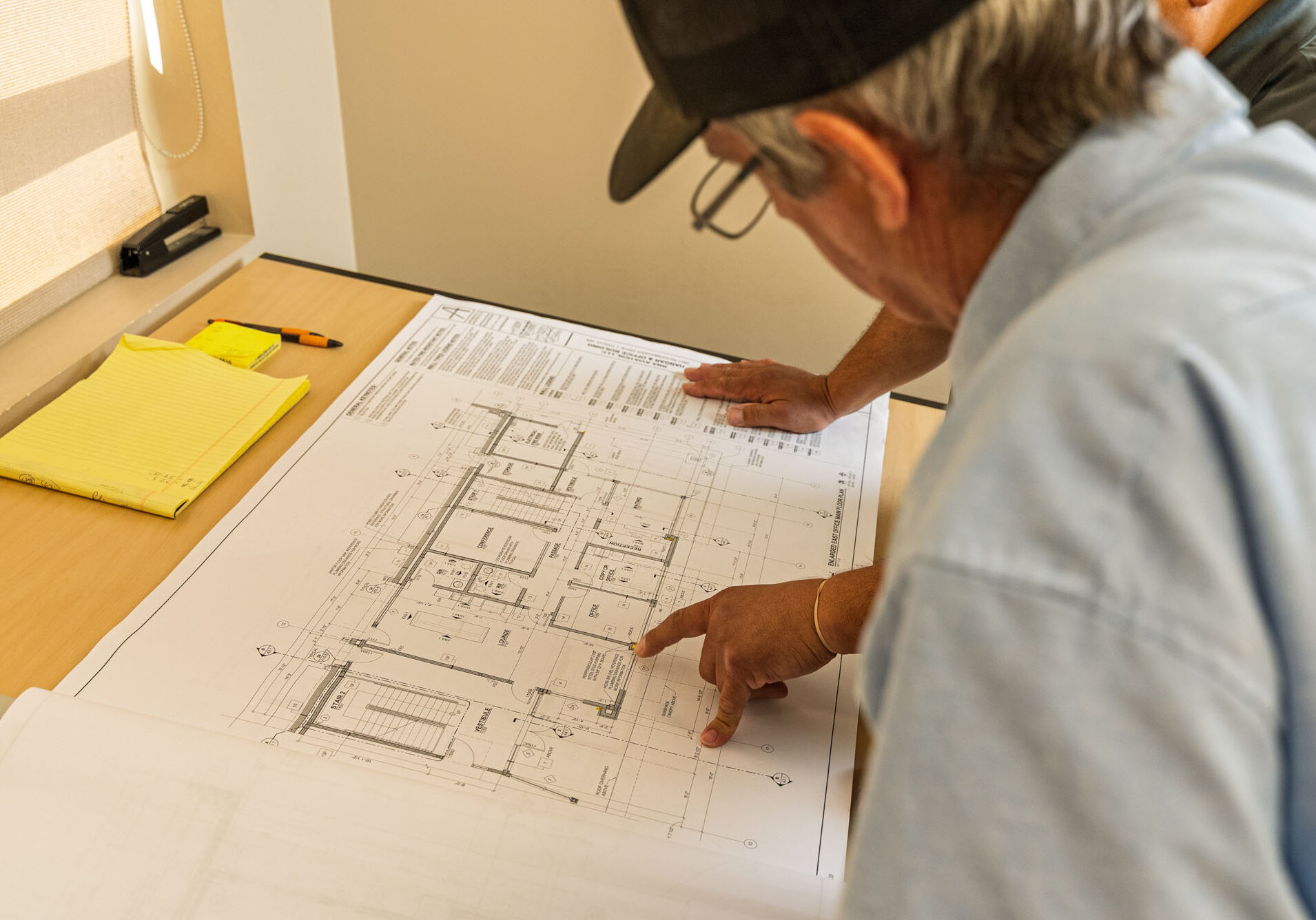 Riggle_Plumbing_0043 Two men reviewing architectural blueprint plans on desk.