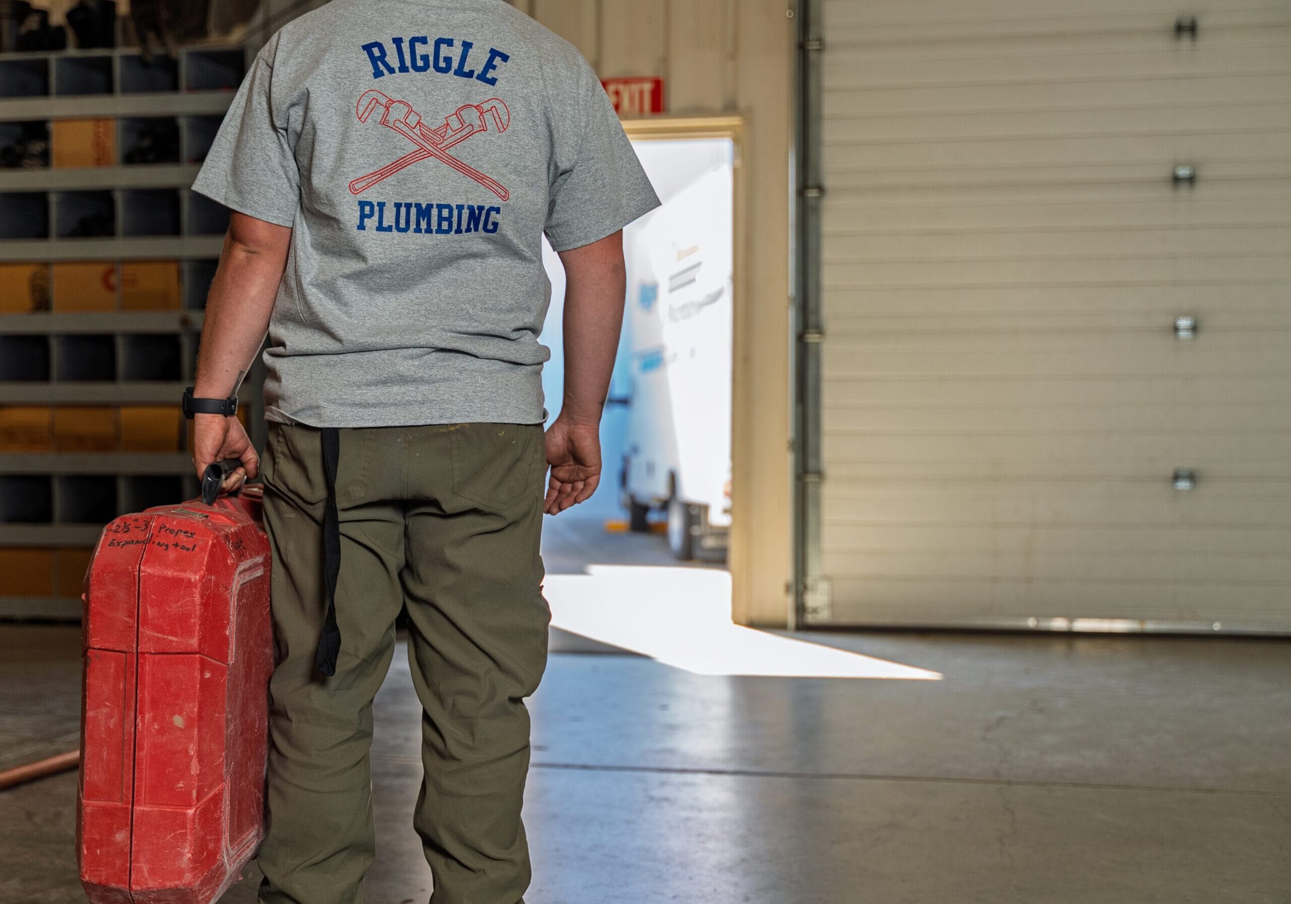 Plumber carrying red toolbox in garage